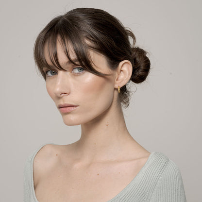 Hex Huggie Earring on left ear zoomed out