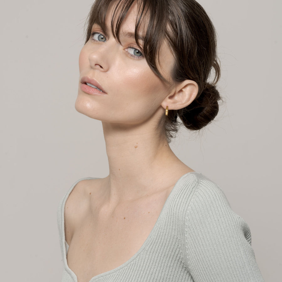 Hex Huggie Earring on left ear zoomed out, with girls face raised