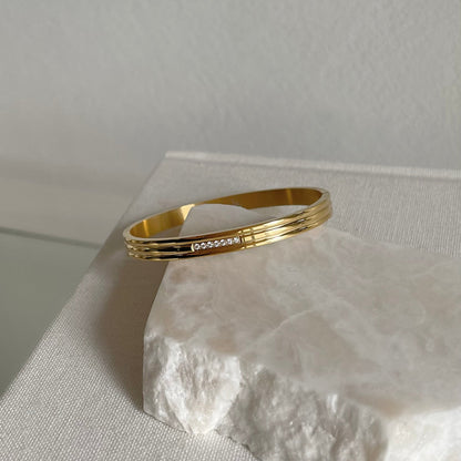 Mia's Gold Bracelet resting on rock